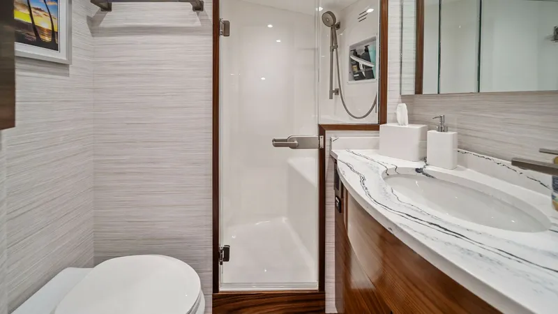 Slide: The Image of Elegant Ensuite Bathroom This stylish ensuite bathroom on the 2024 Viking 64 Convertible features a sleek glass-enclosed shower and a luxurious marble countertop. The rich wood cabinetry adds a touch of warmth, complemented by modern fixtures and ample lighting. A serene and func - 7541845
