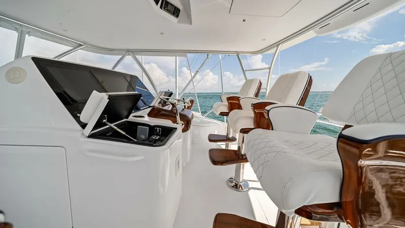 Slide: The Image of Flybridge Helm with Seating The flybridge helm of the 2024 Viking 64 Convertible showcases a state-of-the-art navigation console, complemented by luxurious, cushioned captain's chairs with elegant wood accents. The expansive windows offer panoramic views of the ocean, creating an in - 7541862