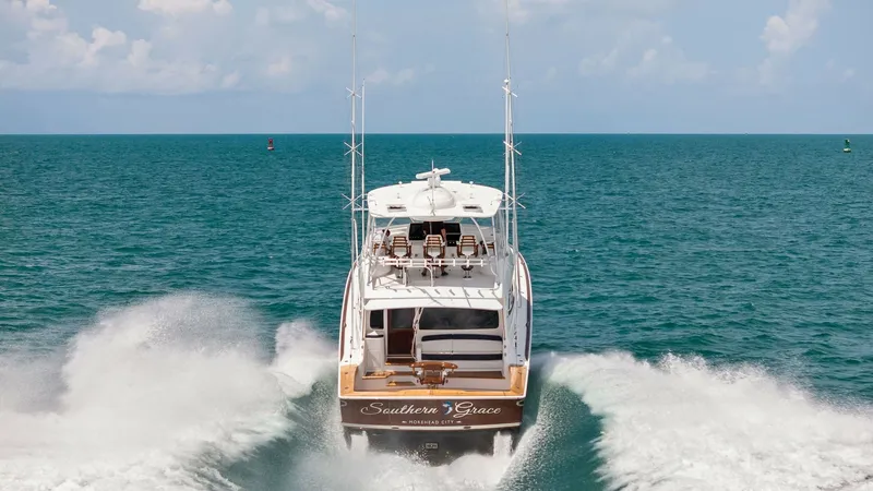 Slide: The Image of Aft View Underway The 2024 Viking 64 Convertible, 'Southern Grace,' is captured in full stride, showcasing its powerful twin engines as it cuts through the water. The spacious aft deck is highlighted, featuring ample seating and a sturdy fishing setup, ideal for both leisu - 7541903