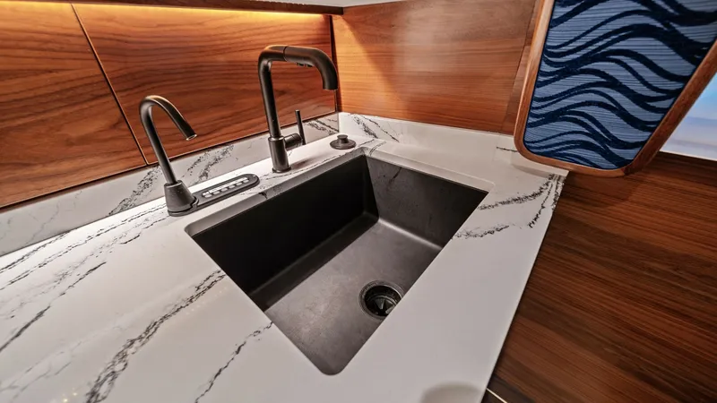 Slide: The Image of Galley Sink with Marble Countertop This elegant galley features a sleek black sink set into a luxurious marble countertop, offering both style and functionality. The modern faucet design complements the high-end aesthetic, while the rich wood grain cabinetry adds warmth to the space. Subtl - 7541821
