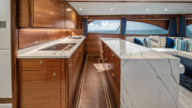 Slide: The Image of Galley with Marble Countertops The galley of the 2024 Viking 64 Convertible features exquisite marble countertops and rich wood cabinetry, offering both luxury and functionality. Ample natural light floods through the large windows, providing stunning views and a bright atmosphere. Thi - 7541840