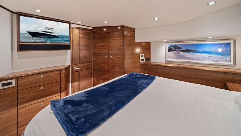 Slide: The Image of Luxurious Master Stateroom Interior The master stateroom of the 2024 Viking 64 Convertible exudes elegance with its rich wood cabinetry and plush bedding. A large window offers serene ocean views, complemented by recessed lighting that enhances the room's ambiance. The space is thoughtfully - 7541842