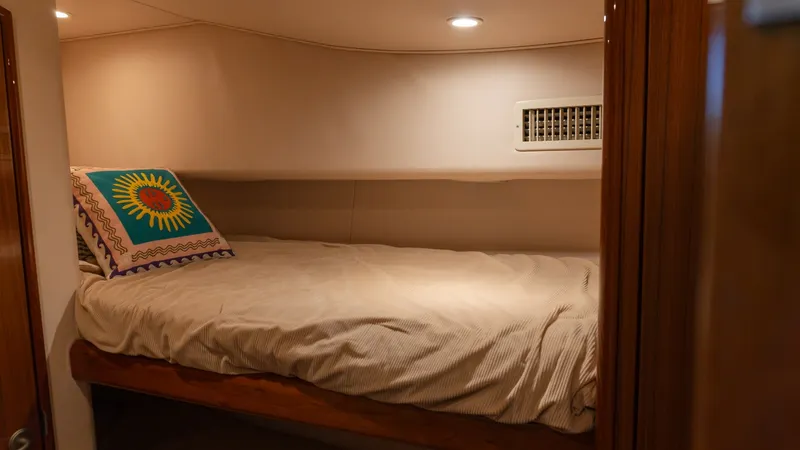 Slide: The Image of 2009 Viking 50 Convertible "Jammin" - Cozy Guest Stateroom with Single Berth This inviting guest stateroom on the 2009 Viking 50 Convertible features a comfortable single berth with plush bedding. Soft ambient lighting complements the warm wood finishes, creating a tranquil retreat. The room is designed with efficient use of space - 7018199