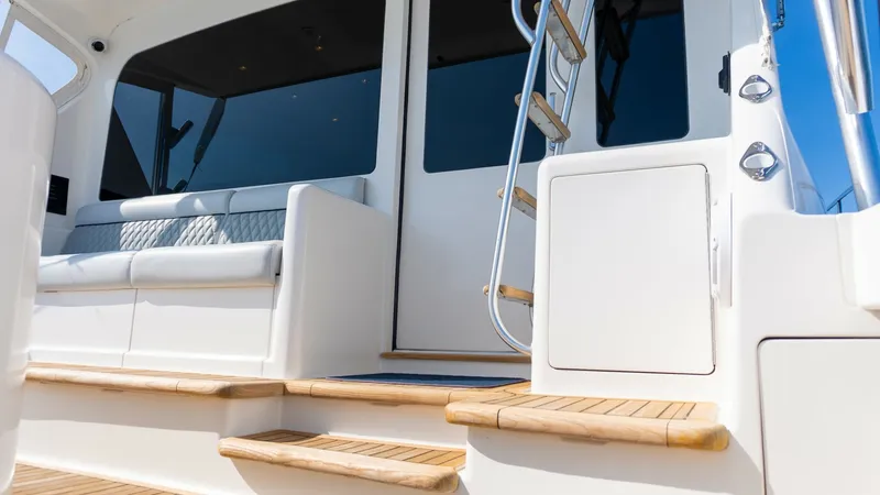 Slide: The Image of 2009 Viking 50 Convertible "Jammin" - Cockpit Entry, Storage compartments, and Ladder Access This image showcases the inviting cockpit entry of the 2009 Viking 50 Convertible, featuring elegant teak steps and a robust stainless steel ladder for easy flybridge access. The seating area is designed with plush, weather-resistant upholstery, providing - 7018211