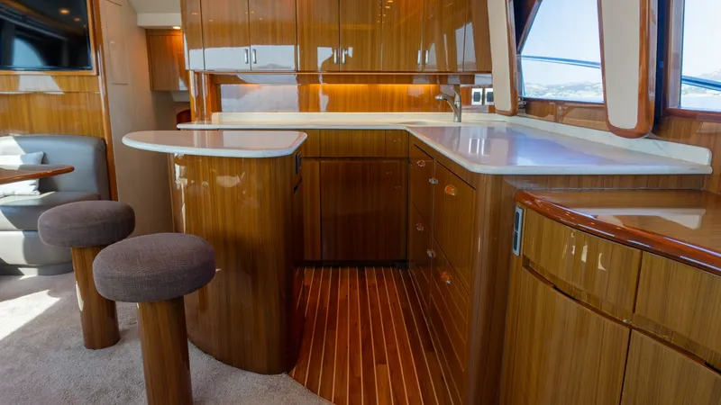 Slide: The Image of 2009 Viking 50 Convertible "Jammin" - Galley with Polished Wood Finished Cabinets and Floor. The galley of the 2009 Viking 50 Convertible 'Jammin' features exquisite polished wood cabinetry and modern countertops, offering both functionality and style. Ambient lighting complements the warm wood tones, creating an inviting atmosphere. The space is - 7018190