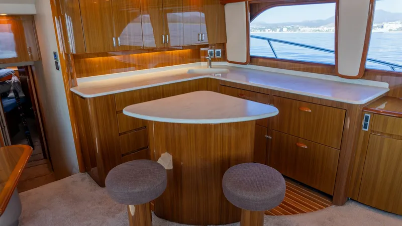 Slide: The Image of 2009 Viking 50 Convertible "Jammin" - The galley of the 2009 Viking 50 Convertible features elegant wood cabinetry and expansive countertops, providing ample space for meal preparation. The breakfast bar with two stools offers a cozy spot for casual dining or socializing. Large windows allow - 7018189
