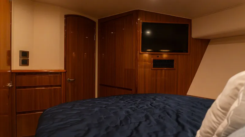 Slide: The Image of 2009 Viking 50 Convertible "Jammin" - Luxurious Master Stateroom Interior The master stateroom of the 2009 Viking 50 Convertible 'Jammin' features elegant wood finishes and ambient recessed lighting. A plush bed with a rich navy coverlet provides a comfortable retreat, while the wall-mounted flat-screen TV offers entertainment. - 7018202