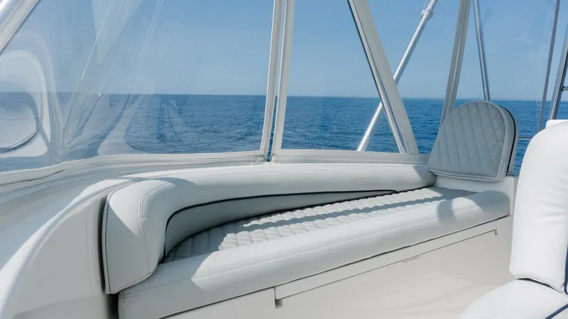 Slide: The Image of 2009 Viking 50 Convertible "Jammin" - A Beautifully Appointed Flybridge Lounge Offering the Perfect Blend of Comfort, Open-Air Living, and Panoramic Views for Unforgettable Moments Underway or at Anchor. The Viking 50 Convertible's flybridge offers a luxurious seating area with panoramic ocean views. The cushioned bench features elegant stitching and a sleek design, providing both comfort and style. Surrounded by clear, protective panels, this space is pe - 7018183