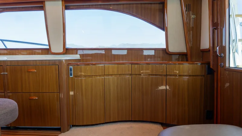 Slide: The Image of 2009 Viking 50 Convertible "Jammin" - Beautifully Crafted Polished Wood Cabinetry Provides Elegant Storage Solutions While Adding Warmth, Sophistication, and Timeless Appeal to the Yacht's Interior. This image showcases the elegant salon interior of the 2009 Viking 50 Convertible, 'Jammin'. The space features high-gloss wood cabinetry that adds warmth and sophistication, complemented by large windows that provide ample natural light and stunning view - 7018191