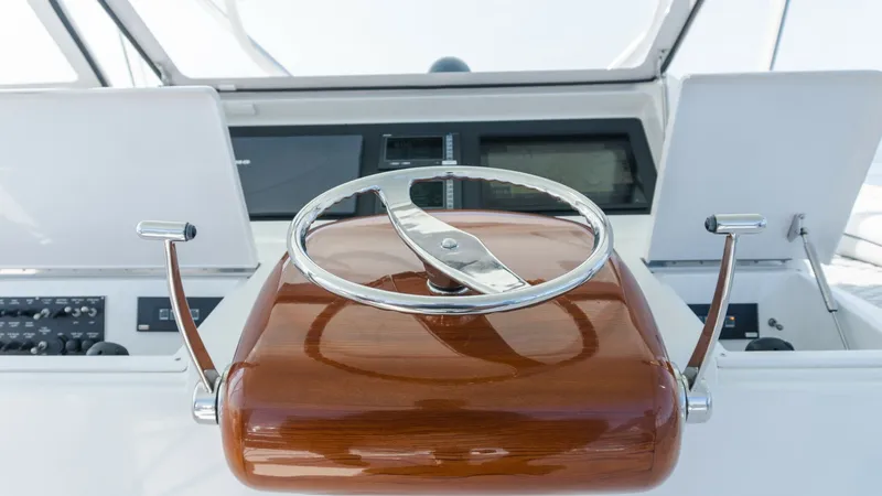 Slide: The Image of 2009 Viking 50 Convertible "Jammin" - Featuring A Sleek, Polished Stainless Steel and Wooden Steering Wheel Station. The helm station of the 2009 Viking 50 Convertible features a sleek, polished wooden steering wheel, perfectly complementing the vessel's sophisticated design. The console is equipped with modern navigation systems, ensuring precise and easy handling. Thi - 7018185