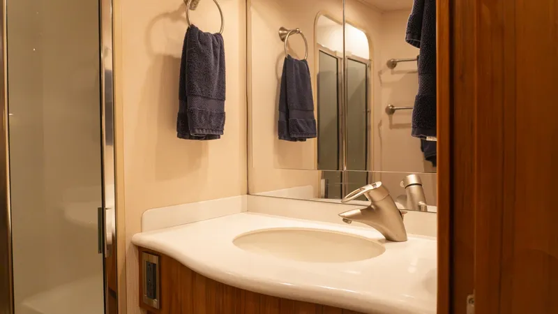 Slide: The Image of 2009 Viking 50 Convertible "Jammin" - Master En Suit Yacht Head This well-appointed yacht bathroom features a sleek vanity with a modern sink and elegant fixtures. The use of warm wood tones complements the clean lines and sophisticated design, while the ample mirror enhances the sense of space. Soft lighting adds to - 7018204