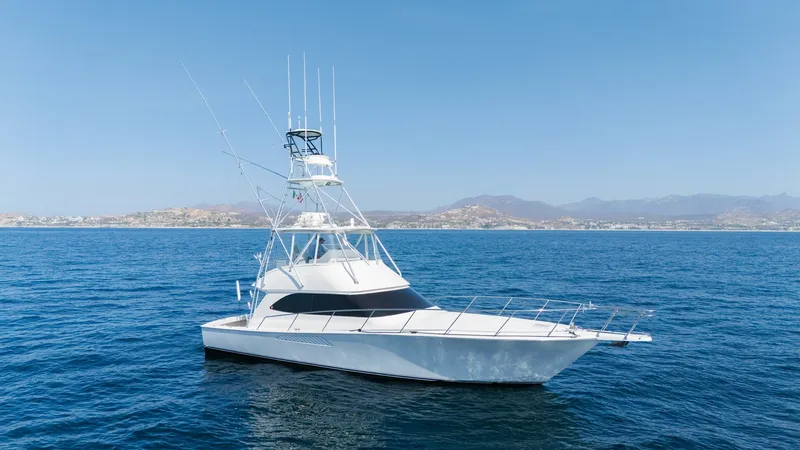 Slide: The Image of 2009 Viking 50 Convertible "Jammin" - The Sleek and Elegant Starboard Profile Showcases the Yacht's Timeless Design and Commanding Presence on the Water. This image showcases the sleek starboard profile of the 2009 Viking 50 Convertible, 'Jammin'. The vessel features a striking white hull with a contrasting dark window line, enhancing its aerodynamic design. The flybridge with an array of antennas and outr - 7018175