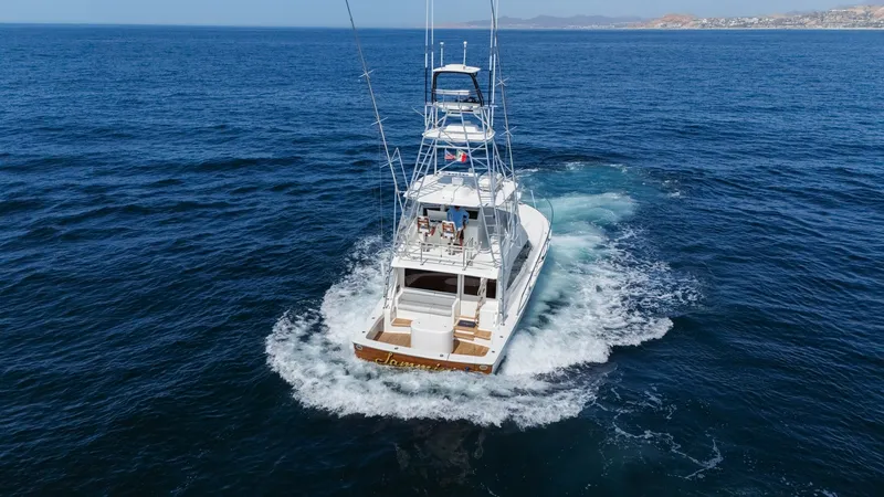 Slide: The Image of 2009 Viking 50 Convertible "Jammin" - Backing Down This striking aerial image captures the stern of the 2009 Viking 50 Convertible, 'Jammin', gracefully cutting through the water. The spacious cockpit is designed for sportfishing enthusiasts, featuring ample seating and storage. The towering flybridge off - 7018217
