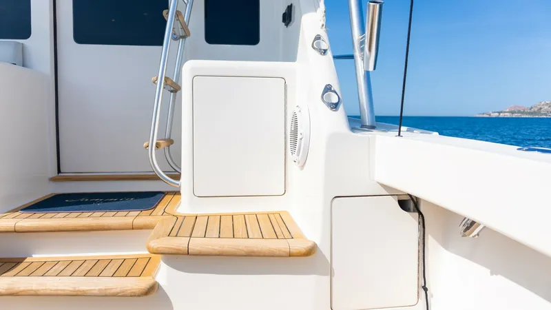 Slide: The Image of 2009 Viking 50 Convertible "Jammin" - Teak Ladder to Flybridge and Storage This image showcases the elegant teak steps leading to the flybridge on the 2009 Viking 50C vessel, Jammin. The craftsmanship is evident in the smooth, polished wood finish that complements the sleek white exterior. Stainless steel handrails provide safet - 7018212