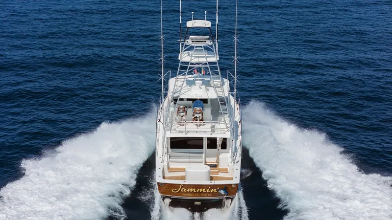 Slide: The Image of 2009 Viking 50 Convertible "Jammin" - Aerial View of Aft Deck in Motion This dynamic aerial shot captures the Viking 50 Convertible 'Jammin' in action, showcasing its powerful wake against the open sea. The spacious aft deck features comfortable seating, perfect for relaxation or fishing, while the flybridge offers commanding - 7018228