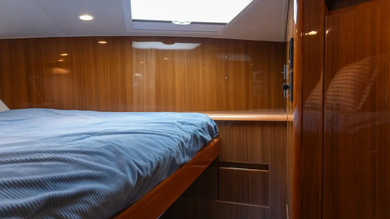 Slide: The Image of 2009 Viking 50 Convertible "Jammin" - Forward Stateroom with Skylight This forward stateroom on the 2009 Viking 50 Convertible features elegant wood paneling and a cozy bed with rich linens. A skylight above provides natural light, enhancing the warm ambience of the space. The room's design maximizes comfort and storage, pe - 7018197