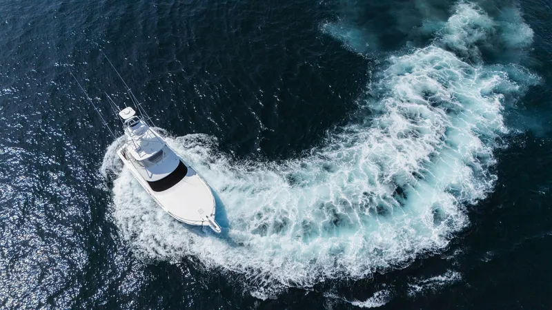 Slide: The Image of 2009 Viking 50 Convertible "Jammin" - Demonstrating Reverse Thrust and Maneuverability This dynamic aerial shot captures the 2009 Viking 50 Convertible, 'Jammin', elegantly carving through the ocean. The vessel's impressive wake highlights its powerful performance and agile handling. The sleek design and expansive deck space are prominently - 7018219