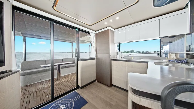 Slide: The Image of Galley and Aft Deck View This image showcases the modern galley of the 2024 Absolute 52 Navetta, featuring sleek cabinetry and premium countertops. The open layout seamlessly connects to the aft deck through sliding glass doors, offering panoramic views and easy access to outdoor - 6851803