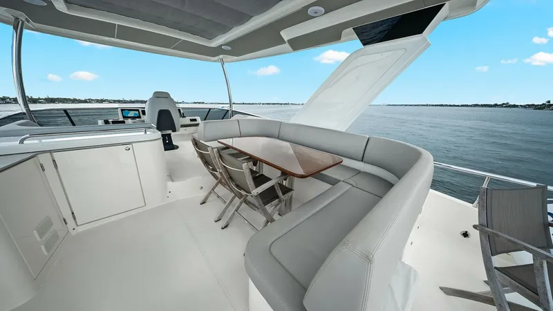 Slide: The Image of Flybridge Seating and Helm The flybridge of the 2024 Absolute 52 Navetta offers a spacious seating area with a sleek, modern design. It features a curved sofa with a stylish wooden table, perfect for alfresco dining while enjoying panoramic views. The helm station is equipped with - 6851788