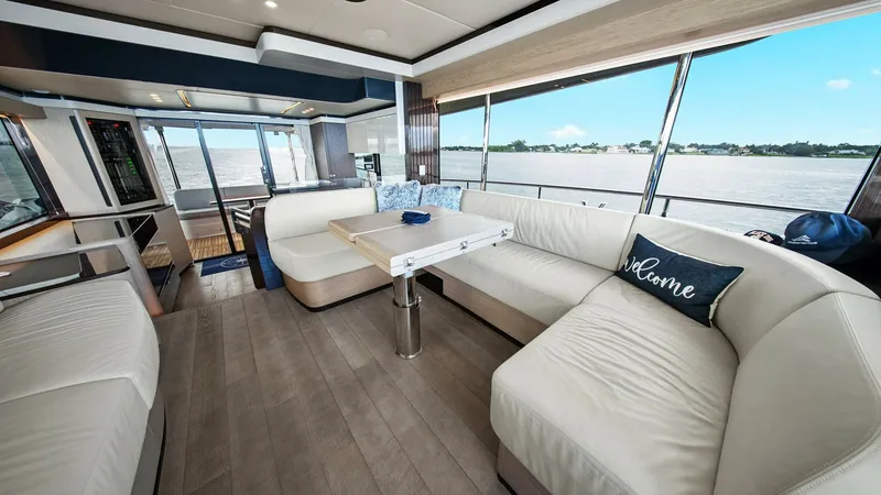 Slide: The Image of Spacious Salon with Panoramic Views The salon of the 2024 Absolute 52 Navetta offers a welcoming and luxurious space with expansive panoramic windows providing stunning water views. The elegant interior features plush, cream-colored seating surrounding a versatile table, perfect for sociali - 6851806