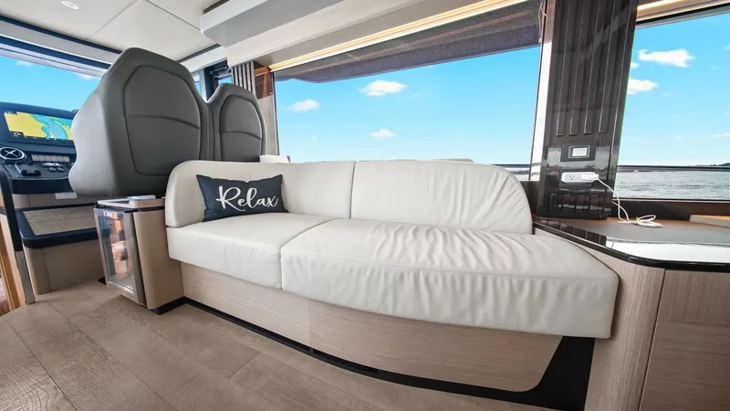 Slide: The Image of Salon Seating Area with Helm View This inviting salon features a plush, white leather sofa positioned for relaxation, enhanced by expansive windows offering panoramic ocean views. The modern helm station is adjacent, ensuring seamless interaction between relaxation and navigation. Elegant - 6851810