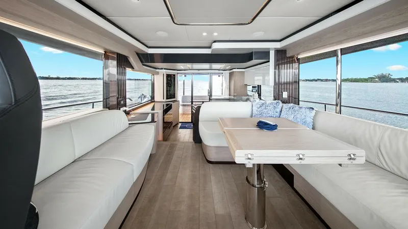 Slide: The Image of Spacious Main Salon with Panoramic Views This elegant main salon on the Absolute 52 Navetta features expansive windows offering breathtaking panoramic views. The modern design includes plush, white seating and a versatile dining table, creating a perfect space for relaxation and entertaining. Re - 6851769