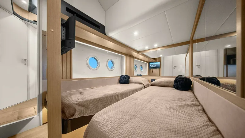 Slide: The Image of Twin Guest Cabin with Portholes This inviting twin guest cabin on the Absolute 52 Navetta features two comfortable single beds with plush bedding, offering a restful retreat for guests. The room is well-lit, thanks to the charming portholes that provide natural light and a nautical ambi - 6851829