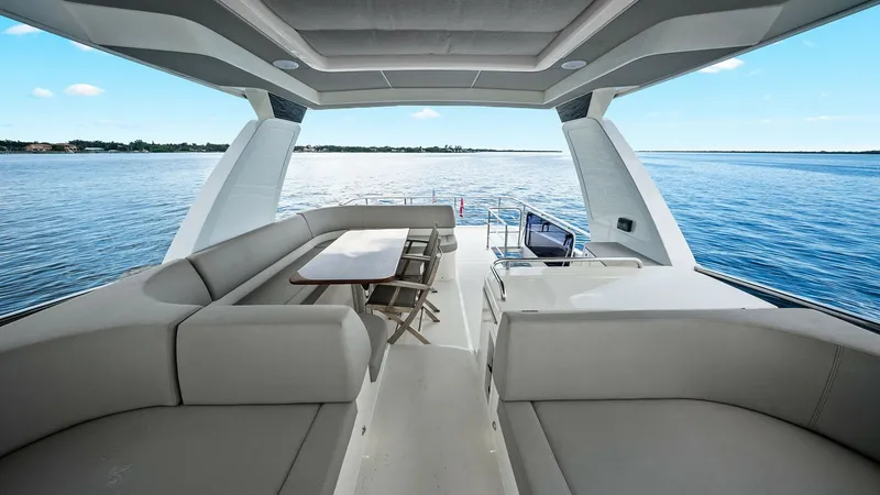 Slide: The Image of Spacious Flybridge with Seating Area The flybridge of the 2024 Absolute 52 Navetta, 'One More', offers a luxurious outdoor seating area, perfect for entertaining. The ample L-shaped sofa surrounds a sleek dining table, providing a comfortable space to enjoy panoramic views. Overhead, a styli - 6851777