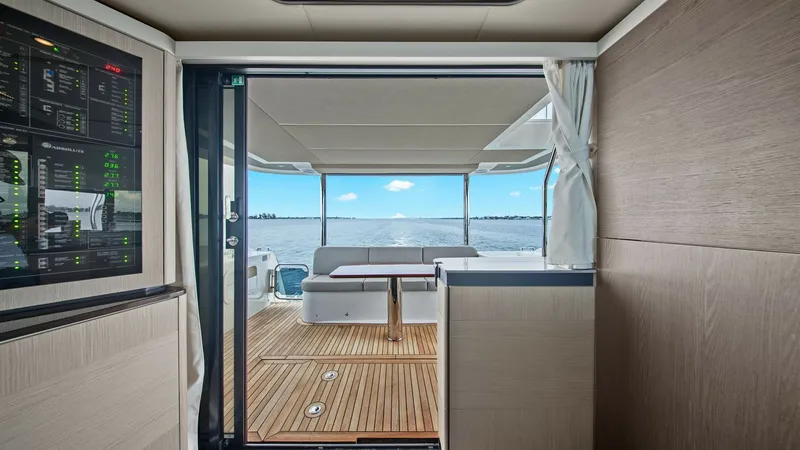 Slide: The Image of Aft Deck View from Interior The image showcases the aft deck of the 2024 Absolute 52 Navetta, viewed from the interior. The sliding glass doors open to reveal a spacious teak deck, complemented by a comfortable seating area perfect for relaxation. The seamless transition between ind - 6851795