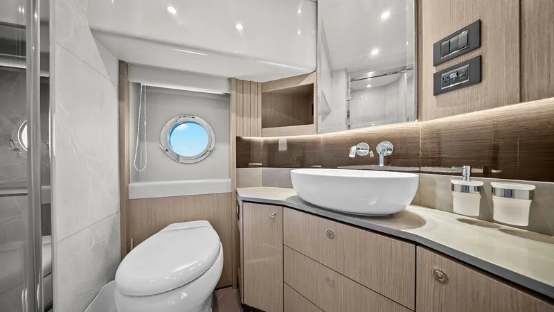 Slide: The Image of Elegant En-Suite Bathroom This sophisticated en-suite bathroom on the 2024 Absolute 52 Navetta showcases modern luxury with its sleek, curved cabinetry and high-gloss finishes. The vessel sink and elegant fixtures are complemented by ample storage and a large mirror, enhancing the - 6851821