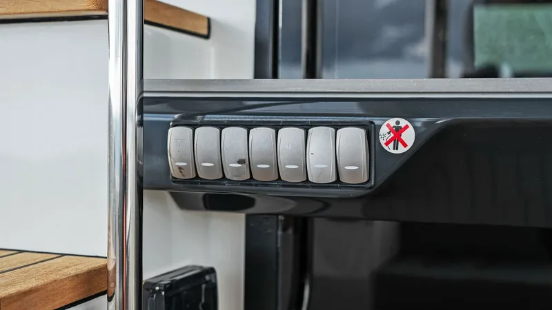 Slide: The Image of Control Panel by Staircase This image highlights the sleek control panel located adjacent to the staircase on the Absolute 52 Navetta. The panel features a set of intuitive switches for easy operation, seamlessly integrated into the yacht's modern design. The staircase, with its po - 6851792