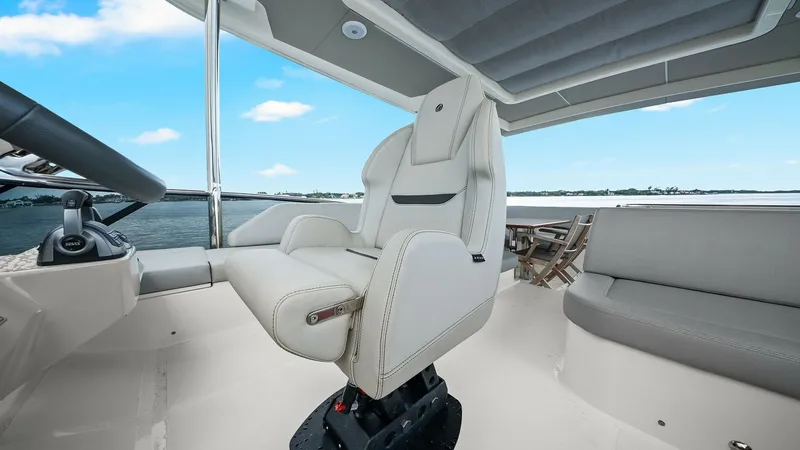 Slide: The Image of Flybridge Helm Station The flybridge helm station of the Absolute 52 Navetta, 'One More', showcases a modern and ergonomic captain's chair with premium upholstery. The area features a panoramic view, complemented by a sleek dashboard with advanced navigation controls. The spaci - 6851774