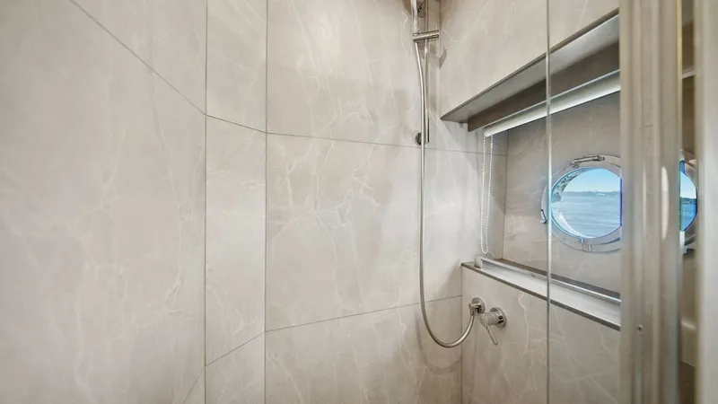 Slide: The Image of Luxurious Ensuite Shower Area This elegant shower area on the 2024 Absolute 52 Navetta features sophisticated marble-like wall finishes, enhancing the sense of luxury. A sleek, modern showerhead complements the minimalist design, while the porthole window provides natural light and a - 6851823