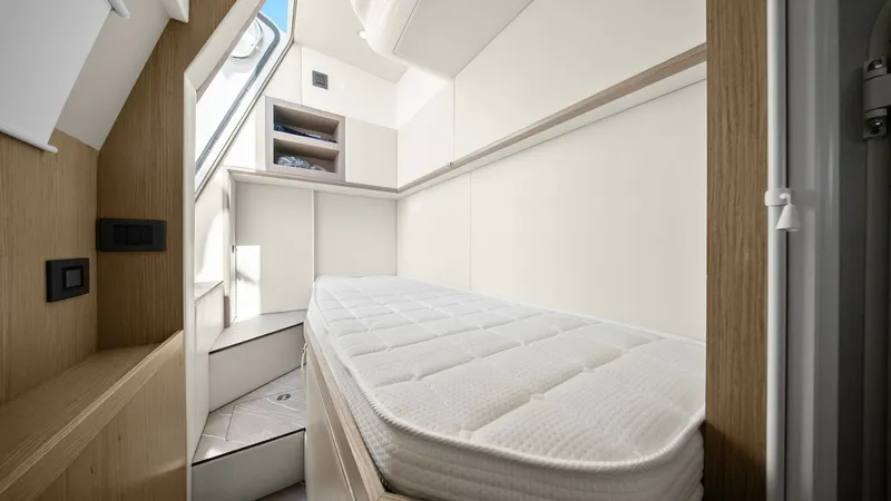 Slide: The Image of Guest Cabin with Single Berth This cozy guest cabin aboard the 2024 Absolute 52 Navetta features a sleek single berth, perfect for restful nights at sea. The cabin showcases a modern, minimalist design with light wood accents and ample storage space. Natural light filters through the - 6851832