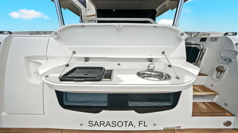 Slide: The Image of Aft Deck Outdoor Kitchen Area This aft deck features a sleek outdoor kitchen area, complete with a built-in grill and sink, perfect for alfresco dining and entertaining. The space is complemented by teak flooring, enhancing the luxurious feel of the Absolute 52 Navetta. Conveniently l - 6851872