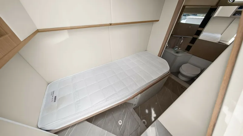 Slide: The Image of Guest Cabin with Ensuite This compact guest cabin features a single berth with sleek, modern design. The space is efficiently utilized, leading to an ensuite bathroom with a toilet and washbasin, offering convenience and privacy. Natural light filters through the window, enhancin - 6851831