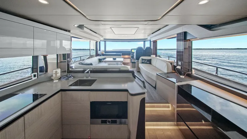 Slide: The Image of Open-Plan Galley and Salon This image showcases the open-plan galley and salon of the 2024 Absolute 52 Navetta 'One More.' The spacious interior features sleek, modern cabinetry and state-of-the-art appliances, highlighted by ample natural light from large panoramic windows. The se - 6851801