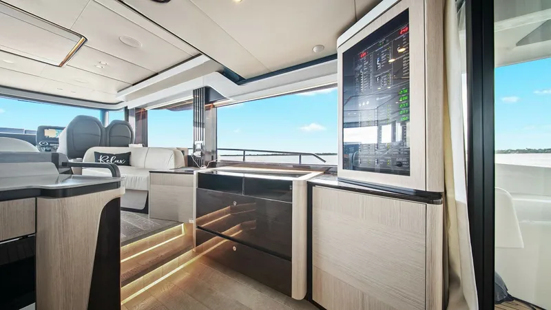 Slide: The Image of Main Salon with Control Station The main salon of the 2024 Absolute 52 Navetta showcases a sophisticated blend of functionality and luxury. Featuring elegant wood finishes and ambient lighting, the space offers a comfortable seating area with expansive views through large windows. The i - 6851804