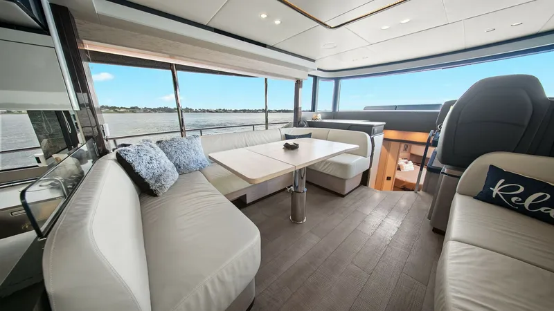 Slide: The Image of Spacious Salon with Panoramic Views Experience the luxurious salon of the 2024 Absolute 52 Navetta, featuring expansive windows that offer stunning panoramic views. The elegantly designed seating area is complemented by plush, modern furnishings and a beautifully crafted dining table. Ample - 6851807