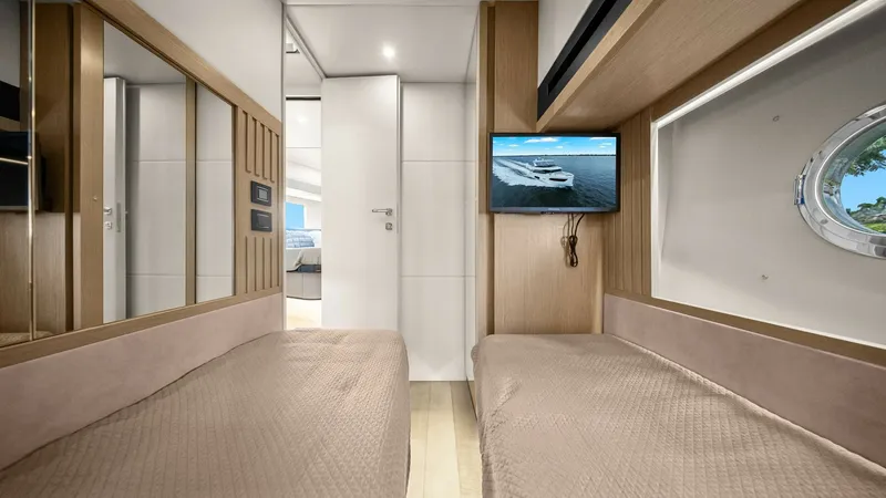 Slide: The Image of Twin Guest Cabin with TV This inviting twin guest cabin on the 2024 Absolute 52 Navetta features plush twin beds with elegant bedding. A wall-mounted TV provides entertainment, while the large mirror enhances the sense of space. Natural light filters through the porthole, creatin - 6851830