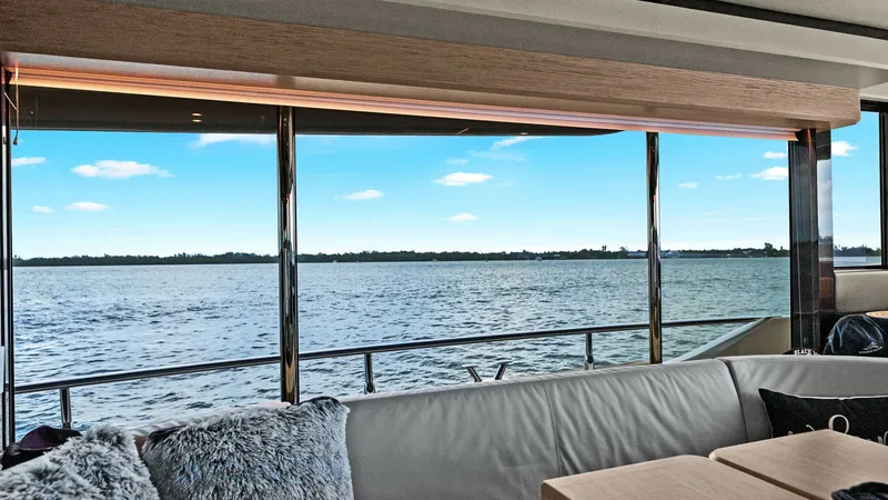 Slide: The Image of Salon with Panoramic Windows The salon of the 2024 Absolute 52 Navetta offers a luxurious seating area with plush cushions and elegant wooden accents. Expansive panoramic windows provide breathtaking views of the water, enhancing the sense of openness and connection to the sea. The s - 6851809