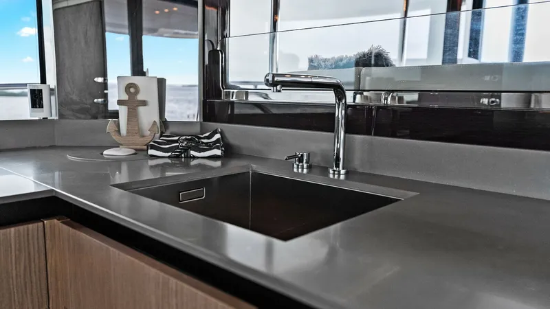 Slide: The Image of Galley with Modern Sink and Counter This image showcases the sleek galley of the 2024 Absolute 52 Navetta. The modern stainless steel sink is set in a chic, solid-surface countertop, providing both functionality and style. Natural light floods the space through large windows, enhancing the - 6851799