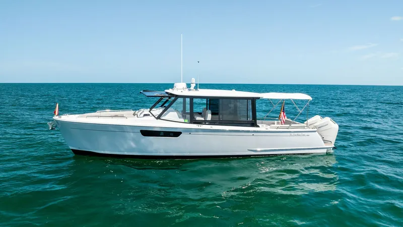 Slide: The Image of Side Profile of MJM M3 This side profile of the 2025 MJM M3, 'The Sunshine Crew,' showcases its sleek and modern design. The vessel features a clean, streamlined hull with large windows that enhance natural light and visibility. The spacious aft deck is equipped with a practica - 6834940