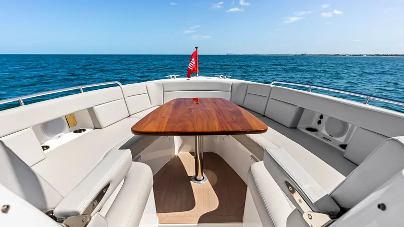 Slide: The Image of Spacious Forward Deck Seating Area This inviting forward deck of the 2025 MJM M3 features plush wrap-around seating, perfect for social gatherings or relaxing under the sun. The elegant wooden table at the center provides a stylish touch, complemented by unobstructed views of the open sea. - 6834904