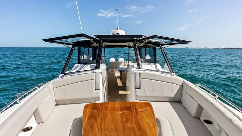 Slide: The Image of Spacious Cockpit with Seating and Table The cockpit of the MJM M3 offers an inviting space with plush, wrap-around seating and a polished wooden table, perfect for social gatherings. Overhead, sleek glass doors open wide, seamlessly connecting the interior with the panoramic ocean views. The de - 6834910