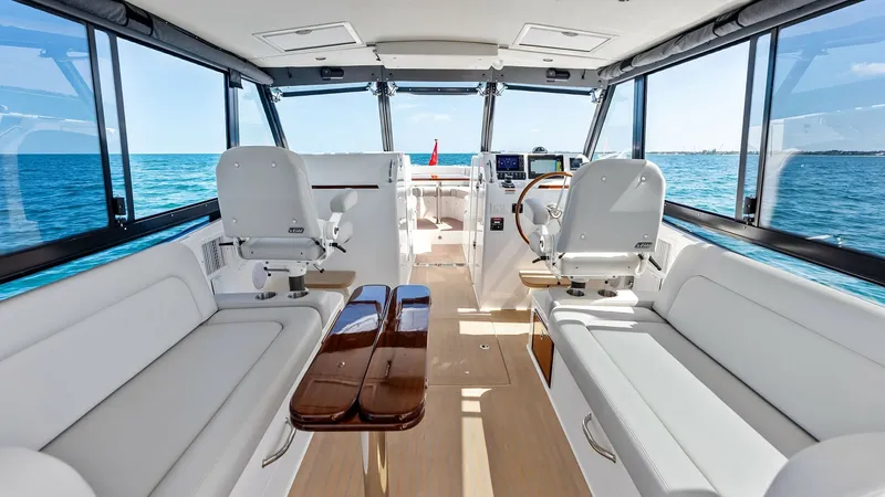 Slide: The Image of Spacious Cockpit and Helm Area The Sunshine Crew's cockpit offers a luxurious blend of comfort and functionality, featuring plush seating and a sleek wooden table ideal for social gatherings. The helm is equipped with advanced navigation instruments and a panoramic view, ensuring a sea - 6834907