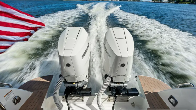 Slide: The Image of Twin Outboard Engines in Action The image showcases powerful twin Mercury outboard engines propelling 'The Sunshine Crew' with impressive speed across the water. The engines are mounted on a sleek teak swim platform, emphasizing the vessel's robust performance and modern design. The wak - 6834931