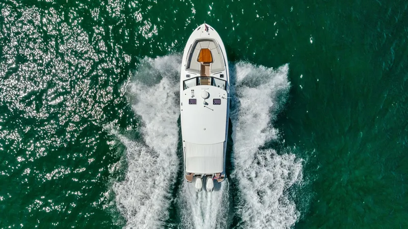 Slide: The Image of Aerial View of Yacht Underway This overhead shot showcases the sleek design of the 2025 MJM M3, The Sunshine Crew, cutting effortlessly through the water. The vessel's powerful dual engines create elegant wakes, highlighting its performance capabilities. The sunlit deck and modern lay - 6834958