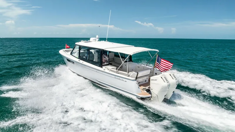 Slide: The Image of Aerial View of MJM M3 Aft Deck This dynamic shot captures the sleek aft deck of the 2025 MJM M3 in action, highlighting its powerful dual outboard engines slicing through pristine waters. The vessel's elegant design features a spacious, covered cockpit area, perfect for leisurely cruis - 6834956