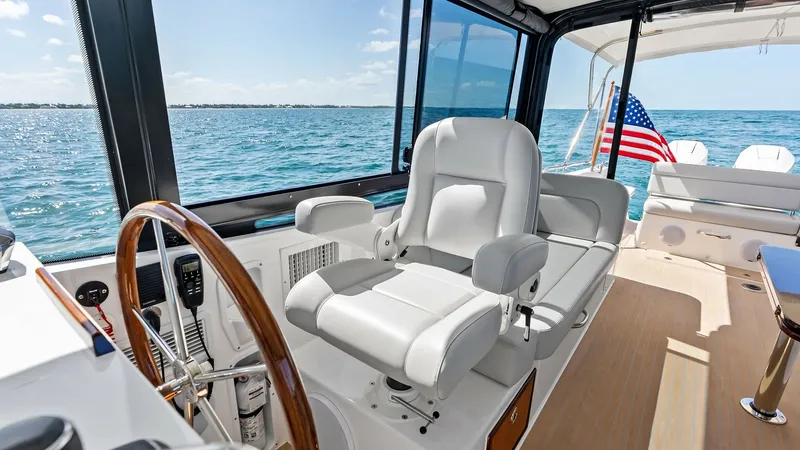 Slide: The Image of Helm Station with Ocean View The helm station of The Sunshine Crew offers a commanding view of the open ocean. Featuring a sleek wooden steering wheel and a plush captain's chair, this area combines functionality with comfort. The large windows provide ample natural light and unobstr - 6834913